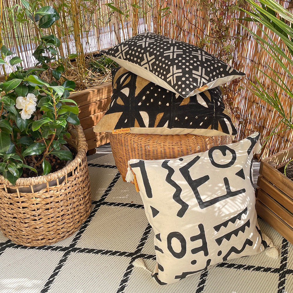 Plusieurs coussin en bogolan sur pouf et tapis de couleurs noirs marron et blanc écru-Several bogolan cushions on ottoman and rugs in black, brown and ecru white colors