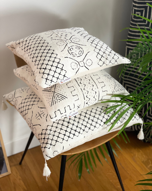 coussin bogolan noir et blanc avec pompon aux extrémité sur une chaise -black and white bogolan cushion with pompom at the ends on a chair