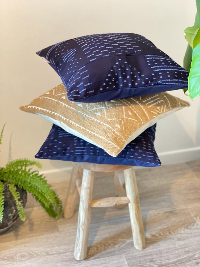 Coussin bleu indigo et ocre de forme carrée empilée l'un sur l'autre sur tabouret - Indigo blue and ocher square cushion stacked one on top of the other on a stool