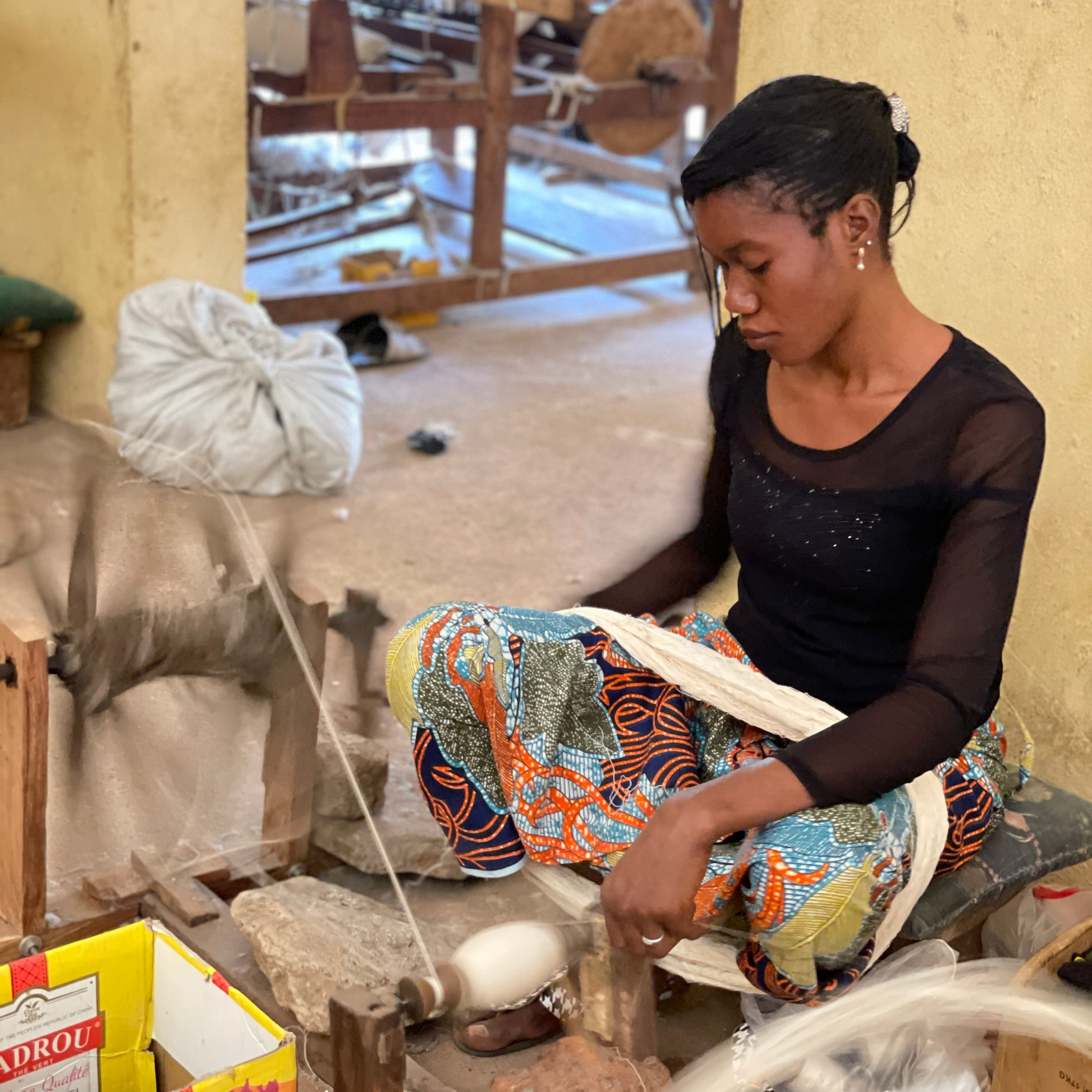 une femme assise entrain de bobiner du fils 
