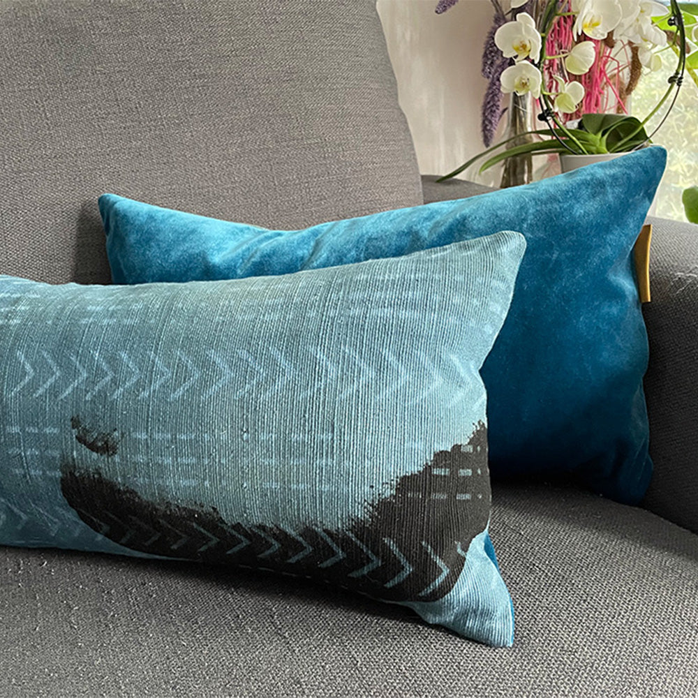 Coussin de forme rectangle de couleurs bleu indigo et motifs noir bogolan au dos velours bleu de canard sur canapé gris - Rectangular cushion in indigo blue colors and black bogolan patterns with duck blue velvet back on gray sofa
