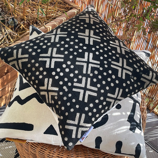 Coussin de forme carrée empilé l'un sur l'autre de couleur noir et blanche avec des motifs blancs écru et des motifs noirs bogolan - Square-shaped cushion stacked one on top of the other in black and white with ecru white patterns and black bogolan patterns