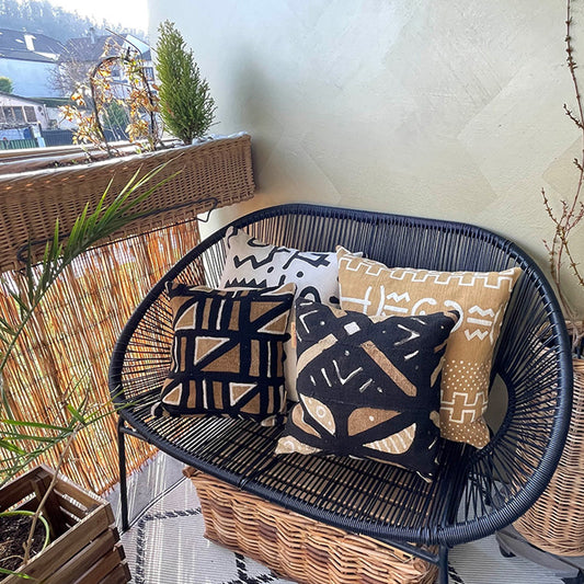 Coussin sur canapé noir en bogolan de couleur ocre avec des motifs géométrique - Cushion on black sofa in ocher-colored bogolan with geometric patterns